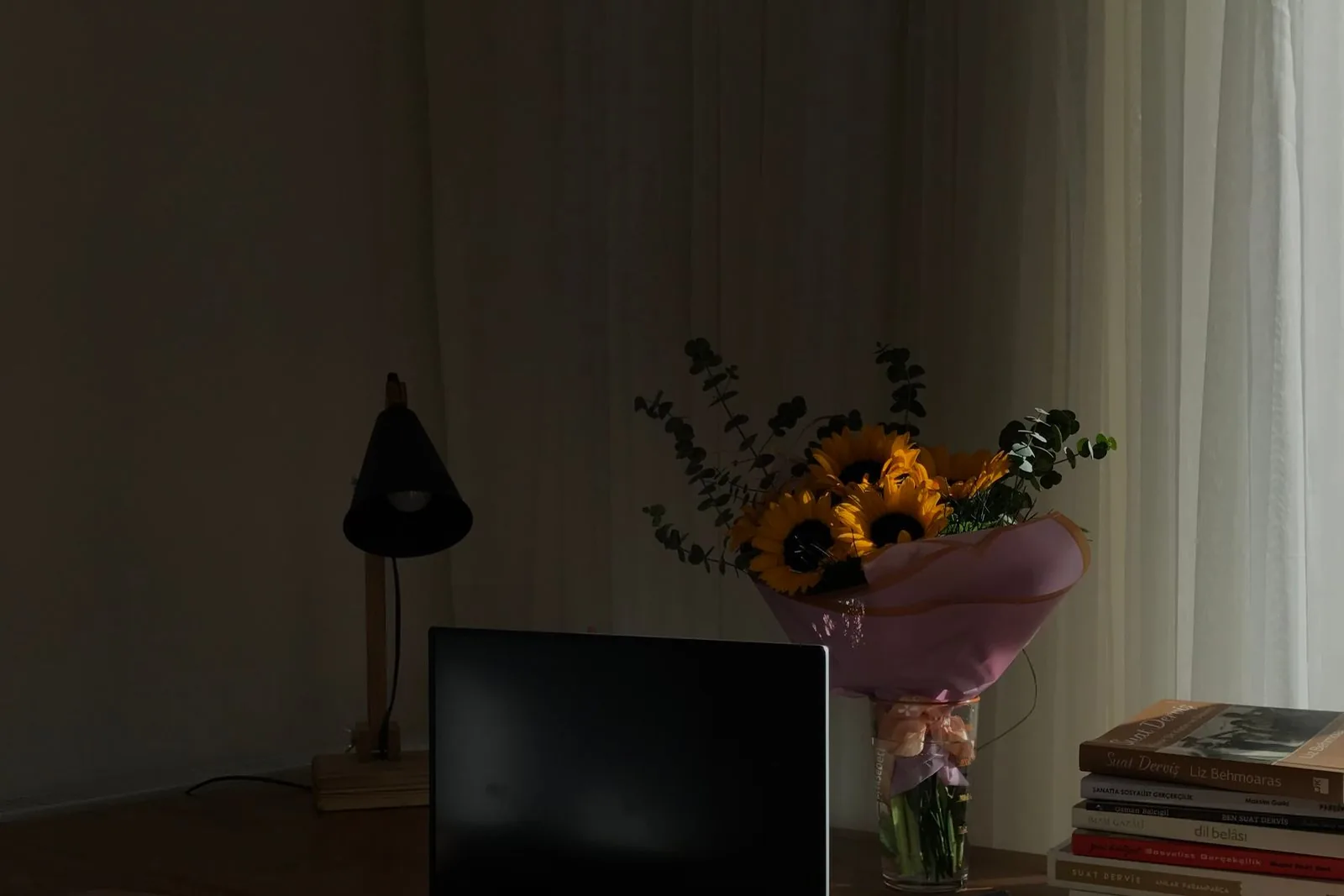 Writing desk with a laptop, books and fresh flowers