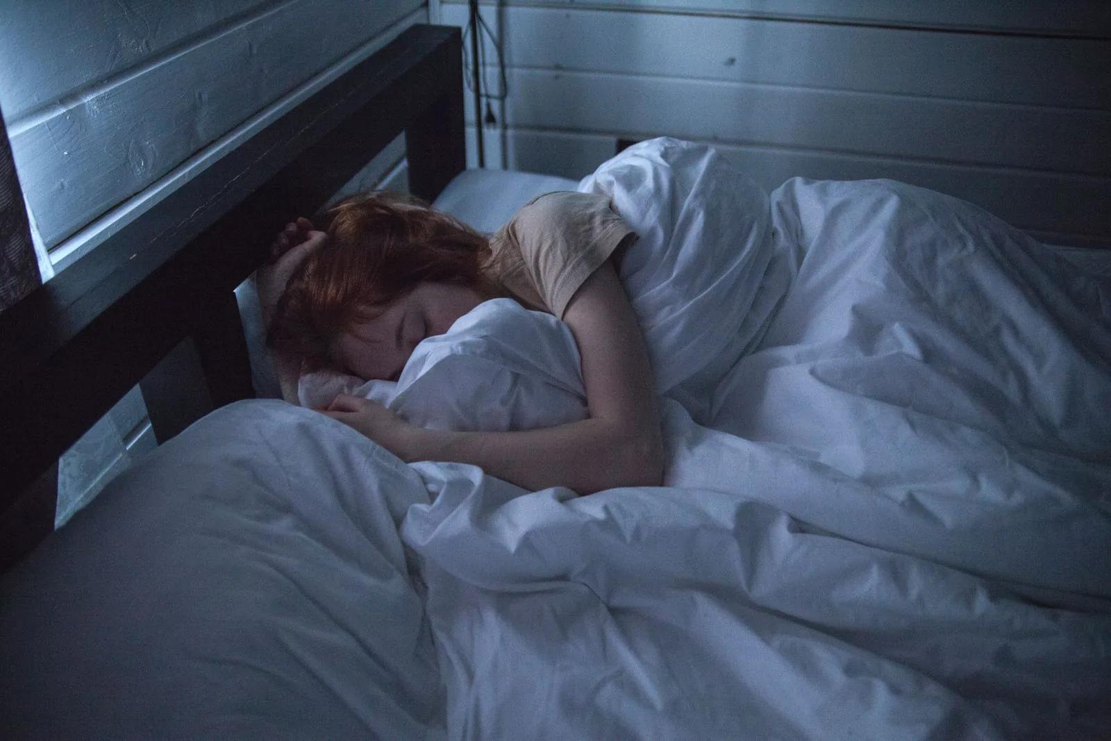 Woman sleeping peacefully in a dim, cool bedroom at night