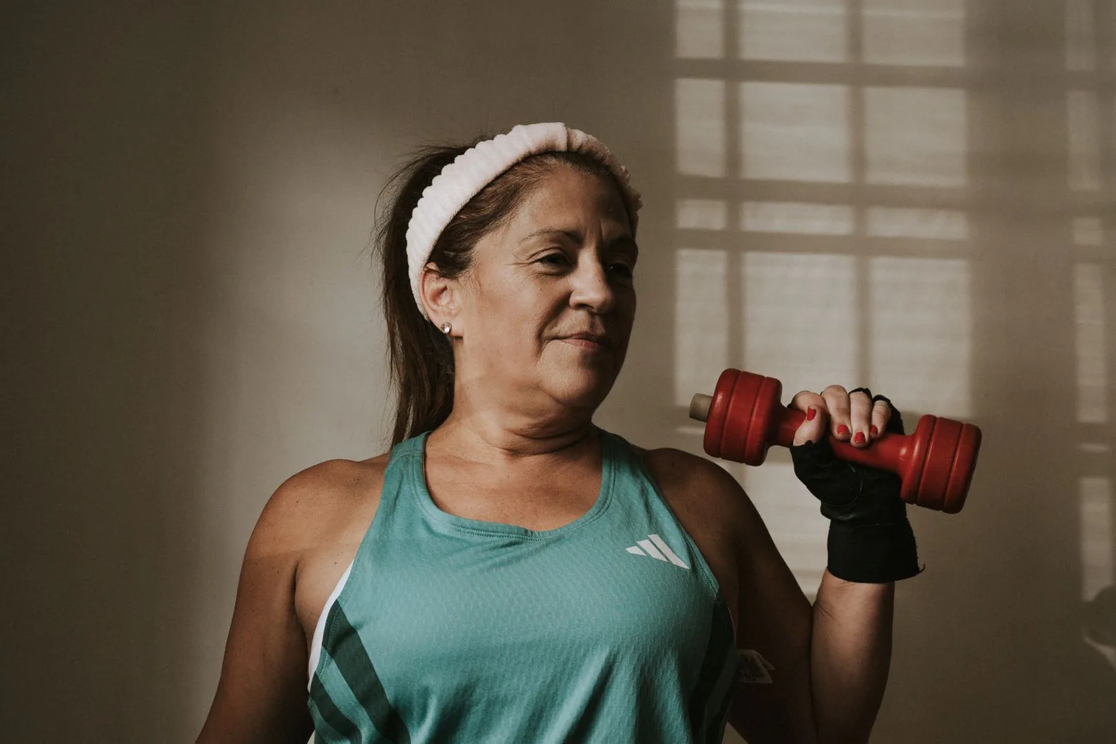 Middle-aged woman exercising with a dumbbell at home